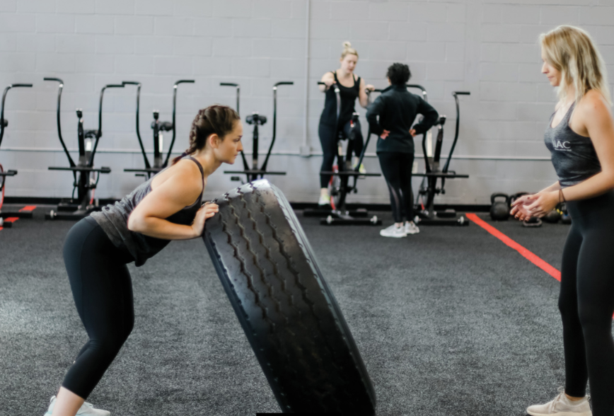 personal trainers throwing a tire