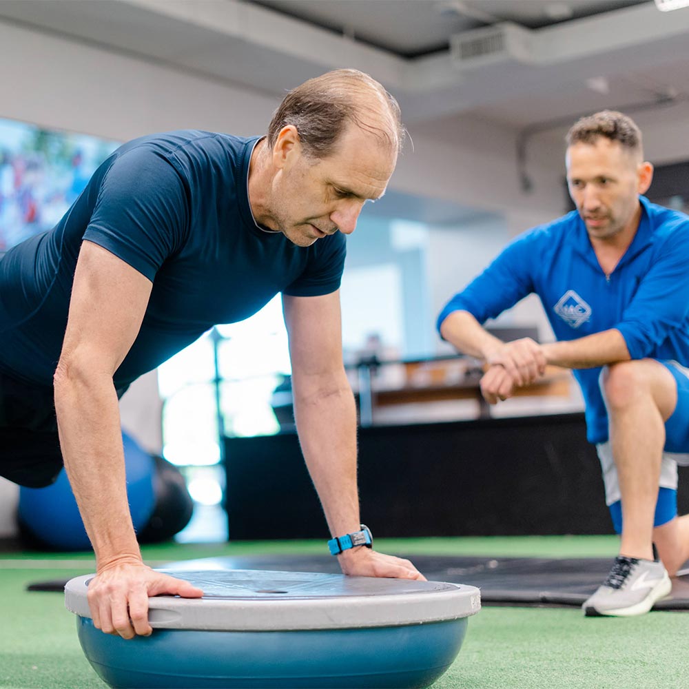 a newtown athletic club trainer working with a client on a bosu ball