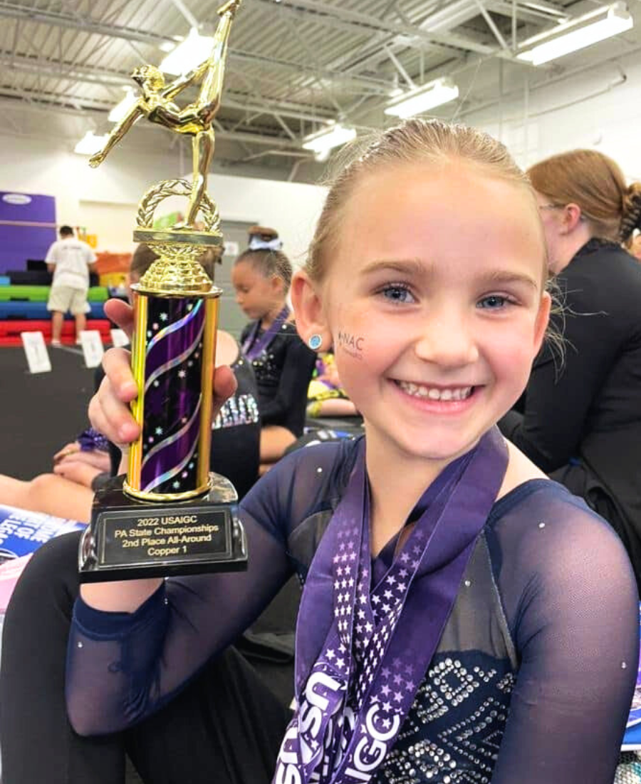newtown athletic gymnast holding a PA state championship trophy