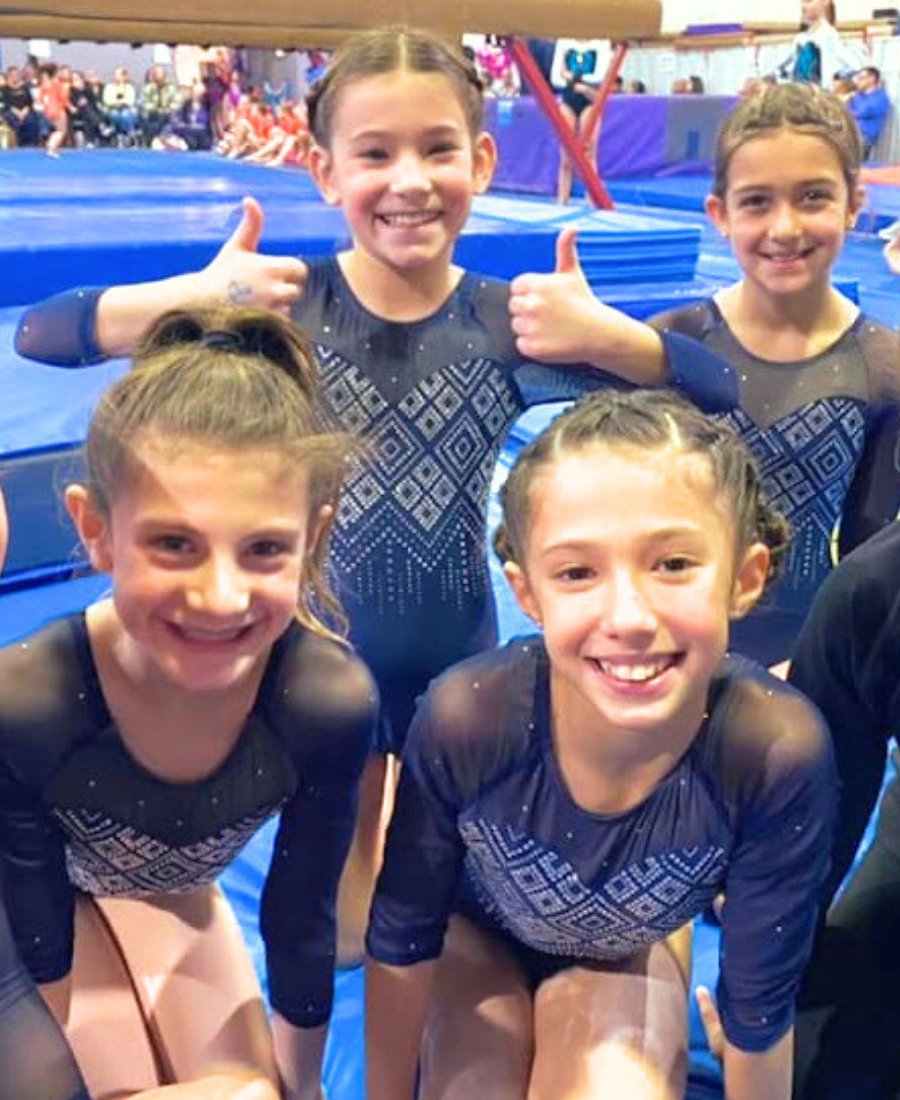 newtown athletic club girls gymnastics team smiling and givng a thumbs up
